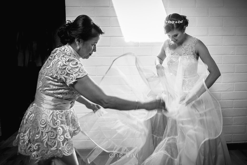 Madre ayuda con el vestido de novia a su hija