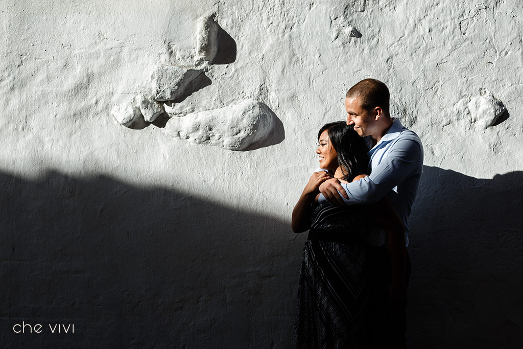 Novio abraza a su novia sbre una pared blanca en Centro historico de Quito
