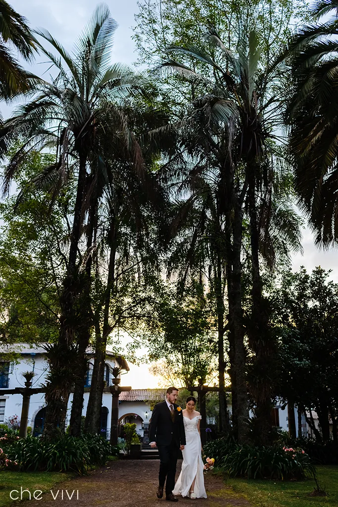 Pareja caminando en jardín de hacienda el Cortijo con árboles Quito.