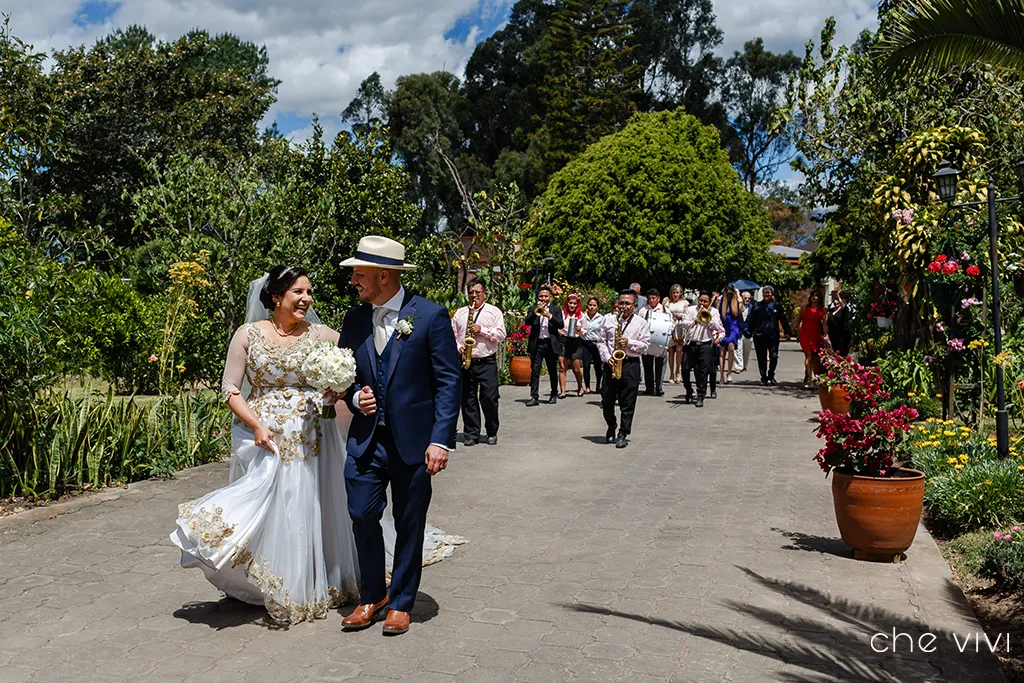 Pareja caminando con banda de pueblo detrás tocando música Quito boda