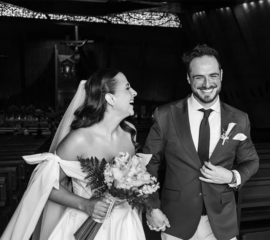 Novia y novio salen de la iglesia sonriendo felices