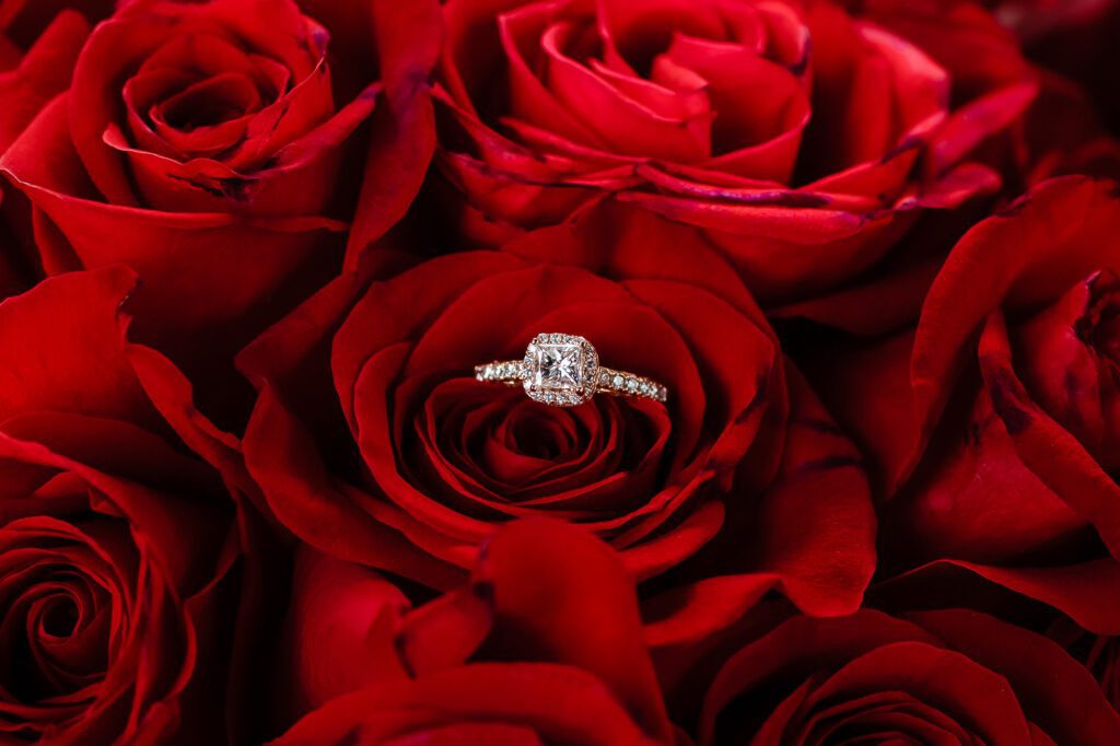 Primer plano de un anillo de diamantes descansando sobre un ramo de rosas rojas intensas en el Hotel Casa Gangotena, Quito. Fotografía de detalles que resalta el romance clásico en el Centro Histórico.