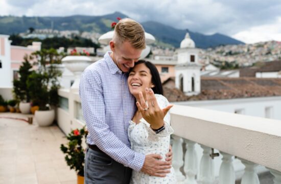 Novia emocionada mostrando su anillo de compromiso tras una pedida de mano en la terraza del Hotel Casa Gangotena. Al fondo, las cúpulas del Centro Histórico de Quito en una captura llena de lágrimas de alegría.