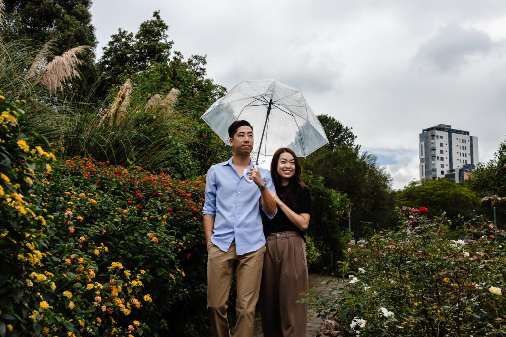 Pareja disfrutando de un paseo bajo la lluvia con un paraguas transparente en el Jardín Botánico de Quito. Capturamos momentos felices sin importar el clima, manteniendo la naturalidad de tu historia.