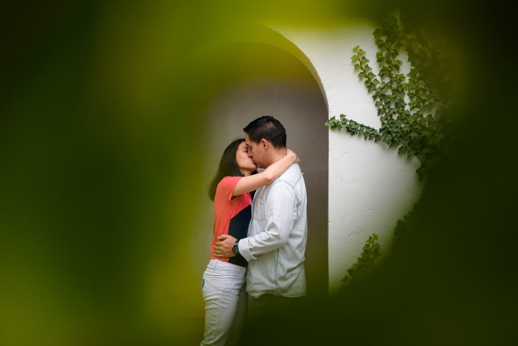 Beso romántico enmarcado por vegetación natural en el Parque de Guápulo. Usamos dos ángulos diferentes para capturar tu emoción desde una perspectiva completa y cinematográfica.